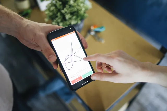 Two people completing a digital transaction with electronic signature on a smartphone screen. When to rebuild loyalty marketing measurement and reporting