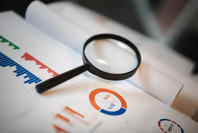 An image showcasing a magnifying glass placed on financial graphs and charts depicting statistical data. Six common loyalty marketing measurement mistakes explained