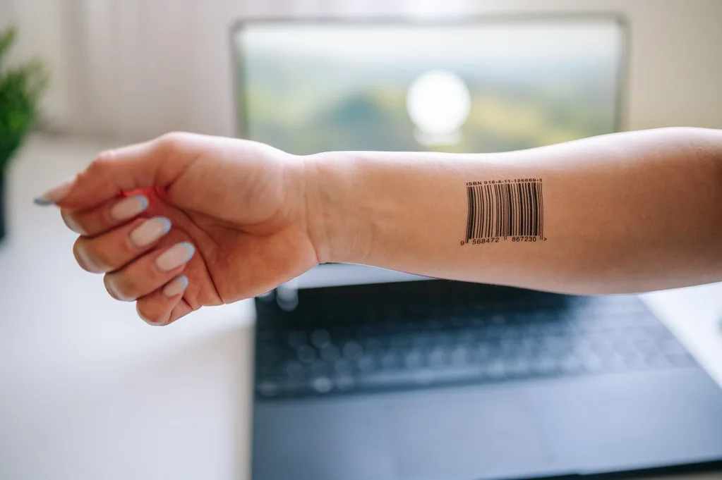 Close-up of a person's arm with bar code in front of a latop's log in screen
